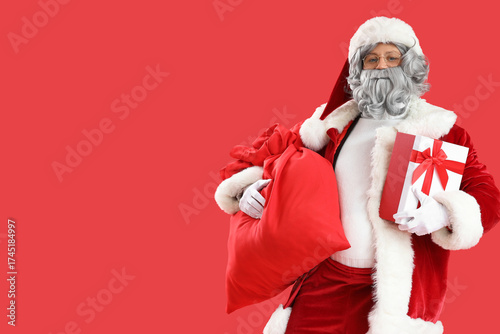 Santa Claus with bag and gift on red background