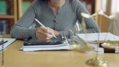 Confident young asian woman studying law with gavel and scales of justice, determined to succeed in legal career.