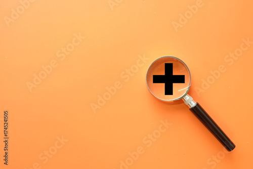 Adding value and creative business growth concept. A magnifying glass over a plus symbol, representing a focus on innovation, adding new features, and increasing company profit and success.