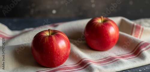 Wallpaper Mural Two vibrant red apples are artfully arranged on a rustic linen cloth with red striped trim, creating a simple still life. Torontodigital.ca