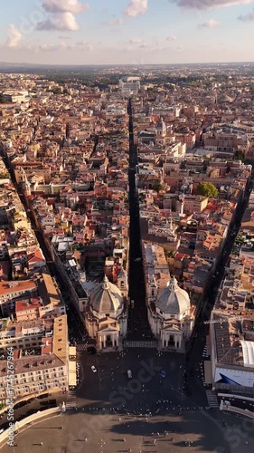 Drone panoramic view of Rome showcasing Santa Maria dei Miracoli and Santa Maria in Montesanto twin churches on Piazza del Popolo, iconic cinematic landmarks of the Eternal City