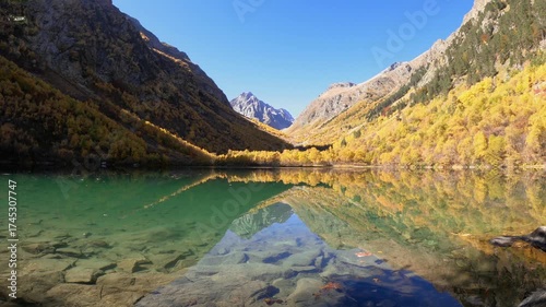Scenic mountain lake with transparent glassy water and autumnal trees.