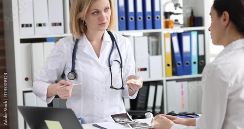Mammalogist shows breast model to woman patient during consultation. Specialist explains diagnosis and recommends screening plan noting risk
