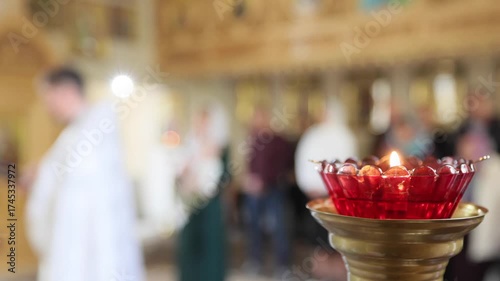 Blurred Religious Ceremony in Church with Priest and Congregation Seen Through Soft Candle Flame in Foreground