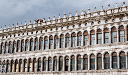 Historic Renaissance Facade with Symmetrical Arched Windows in Venice, Italy – Classical Architecture and Ornate Stone Detailing Under Cloudy Sky