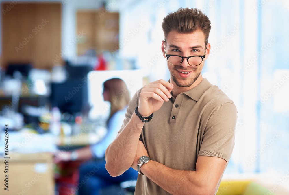 Fototapeta premium Young man standing in a modern office and looking at camera