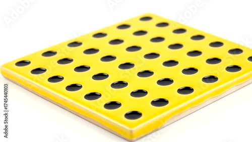 Yellow ceramic tile with black holes, showcasing vibrant design in studio