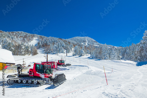 Quadro em tela A freshly groomed ski run with a snowcat and chairlifts under a clear blue sky (