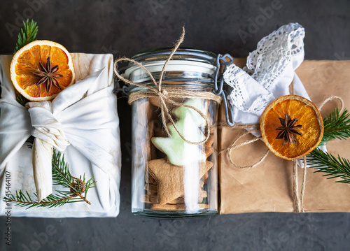 Christmas zero waste, rustic, eco. Three main eco-friendly gift wrapping - furoshiki style (cloth), craft paper, glass (jar). Boxes decorative dried oranges, anise, Christmas tree branch.