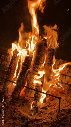 Fire is burning in a fireplace. The fire is very large and is surrounded by logs