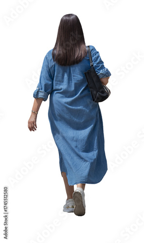 Femme vue de dos marchant en été, portant une robe longue en jean et un sac noir à l’épaule, baskets blanches, tenue estivale