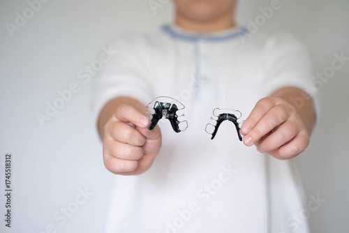 Smiling child showing two removable orthodontic retainers in hands. Dental care, orthodontics, healthy teeth and pediatric dentistry concept.
