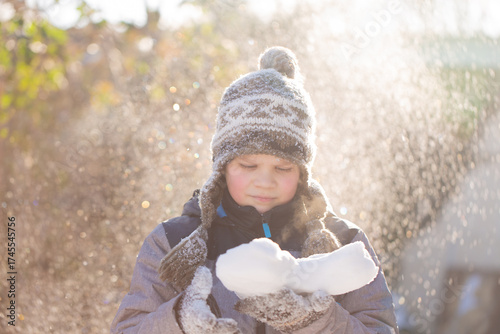 Boy thoughtfully looking at snow heart in sunlight, Valentine Day concept