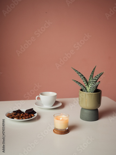 Coffee, Candle, and Dry Dates on White Table with Zebra Haworthia against Peach Wall, Italian Terrace, Vertical Still Life