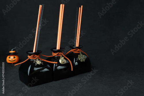 black luxury aroma scent reed diffuser glass bottle on black table to create mystery and luxury ambient bedroom with black cracked cement wall background at night on Halloween day party air freshener
