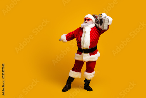 Santa Claus grooving to beats on a boombox while wearing a cheerful red costume on a vibrant yellow background celebrating Christmas