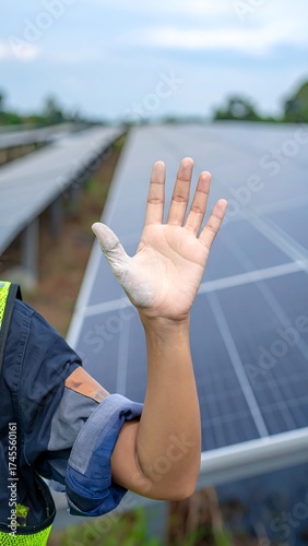 Person's raised hand in front of solar panels