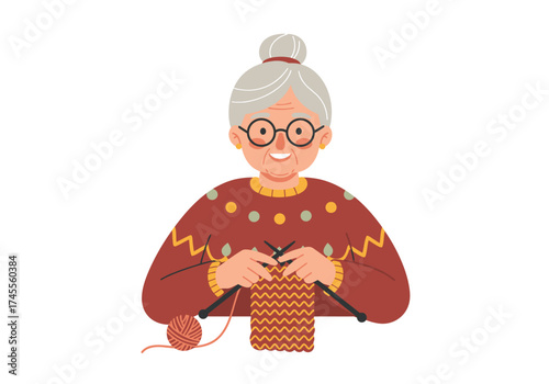 Cheerful elderly woman with grey hair bun and glasses knitting in a red patterned sweater.