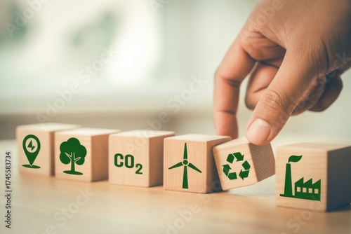 Eco-Friendly Building Blocks: A hand carefully positions a recycling symbol block into a line of environmental icons, emphasizing sustainability and ecological consciousness.