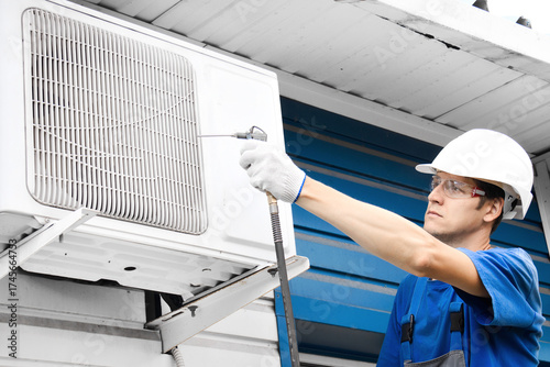 Caucasian male technician cleaning air conditioner unit outdoors.