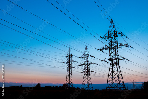three metal poles of high-voltage power lines against the sunset