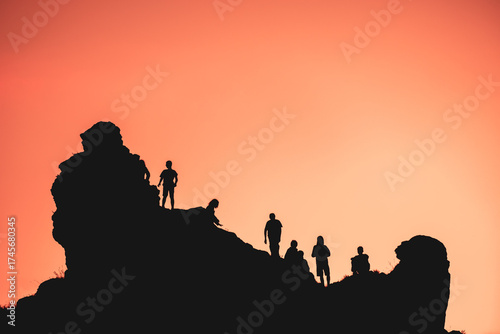 silhouettes of a group of people climbing a mountain