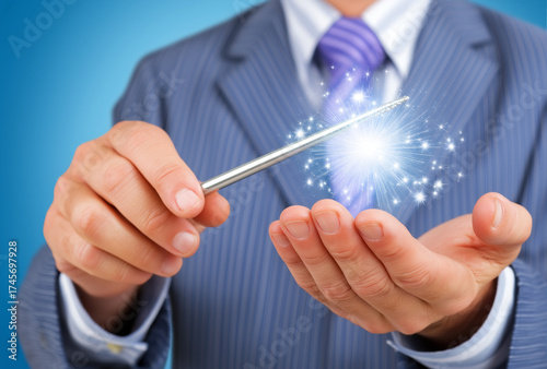 businessman using a magic wand to create glowing sparkles