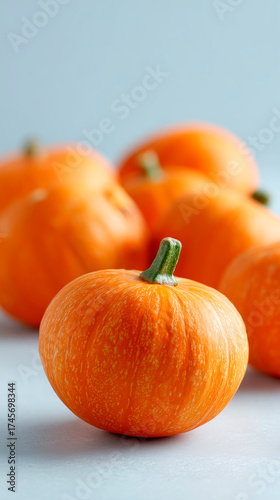 A close-up shows several ripe, orange pumpkins on a simple surface.