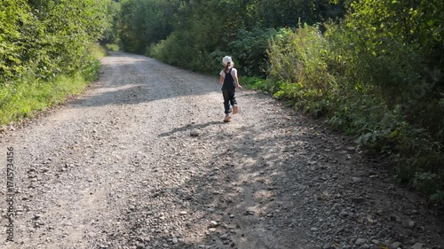 A five-year-old girl walks alone along a gravel road in the forest.