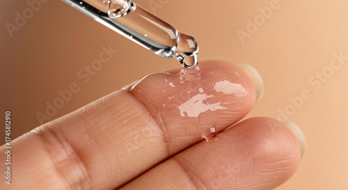 Close-up of dropper releasing serum onto fingertip for tattoo removal  