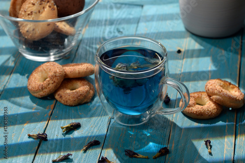 Blue butterfly pea tea in glass cup with cookies on blue wooden table