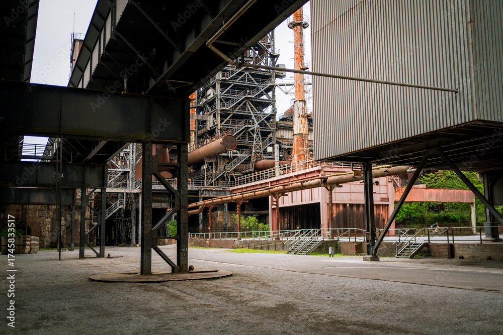 Fototapeta premium Wide-angle view of an abandoned industrial factory featuring rusted pipelines, steel beams, and scaffolding. A perfect scene for industrial design and urban decay themes.