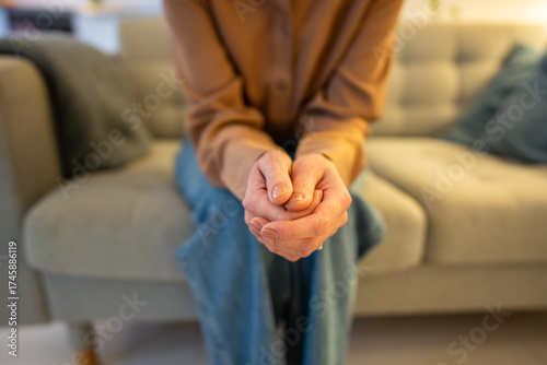 Foto Nervous woman clasped hands anxiously twisting fingers awaiting uncertain news on hospital couch