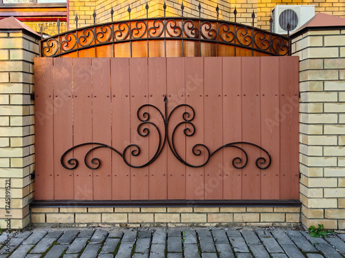 A wooden fence with iron elements between brick pillars. Fencing design concept for urban architecture and landscapes.