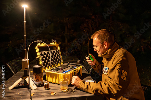 Amateur radio operator in the forest at night, sitting at a table with a portable HF Go-Box setup, communicating off-grid during an outdoor ham radio operation