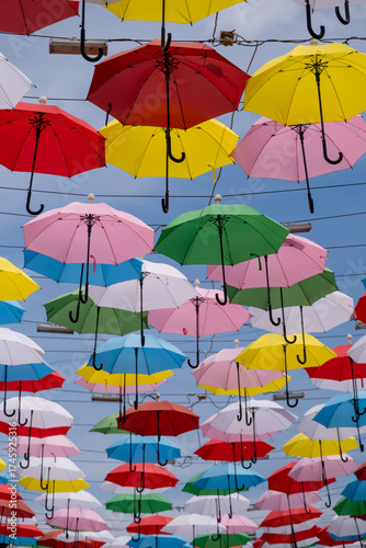 Colorful umbrellas hanging in the sky. Vibrant street decoration with umbrellas. Creative urban decor with hanging umbrellas.