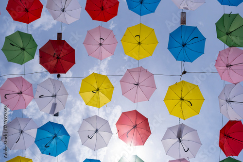 Colorful umbrellas hanging in the sky. Vibrant street decoration with umbrellas. Creative urban decor with hanging umbrellas.