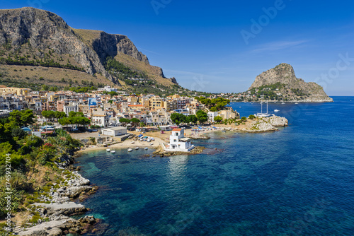 Fototapeta Naklejka Na Ścianę i Meble -  Sant Elia bay beach in Porticello town, Santa Flavia, Sicily, Italy, aerial drone view of Sicilian turquoise waters, rocky cliffs, colorful houses, and Mediterranean coastline panorama in Bagheria