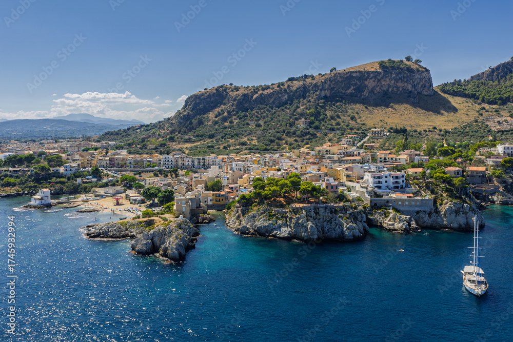 Fototapeta premium Sant Elia bay beach in Porticello town, Santa Flavia, Sicily, Italy, aerial drone view of Sicilian turquoise waters, rocky cliffs, colorful houses, and Mediterranean coastline panorama in Bagheria