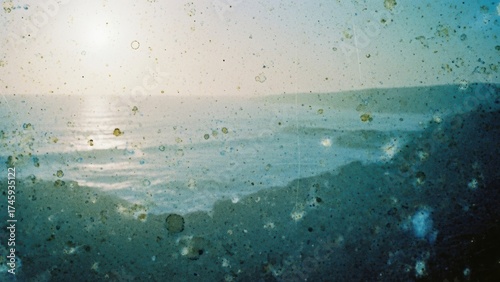 A faded and damaged film photo of a coastal scene, with spots and light leaks.