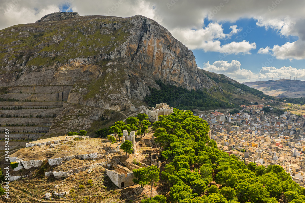 Obraz premium Aerial drone view of Caltavuturo, a historic Sicilian mountain town in Palermo, Italy, featuring its medieval castle, rugged surrounding cliffs, and scenic landscapes of the Madonie Mountains