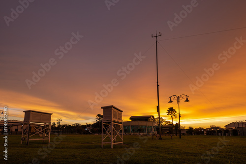 Golden hour over a meteorological field station, where Stevenson screens and anemometers stand ready, quietly capturing the pulse of the atmosphere