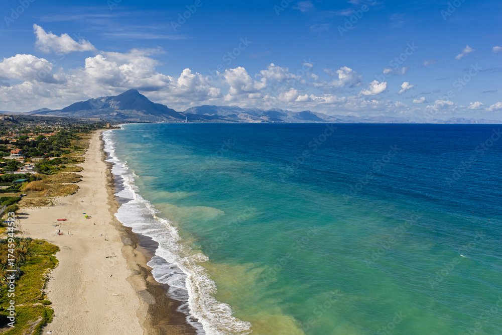 Fototapeta premium Aerial drone view of Lascari Beach, a scenic coastal area near the Madonie Mountains in northern Sicily, Italy, golden sand, turquoise Tyrrhenian Sea waters, and a peaceful Mediterranean landscape