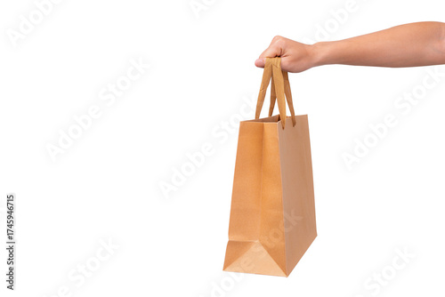Hand holding a blank brown paper bag, isolated on a transparent background.