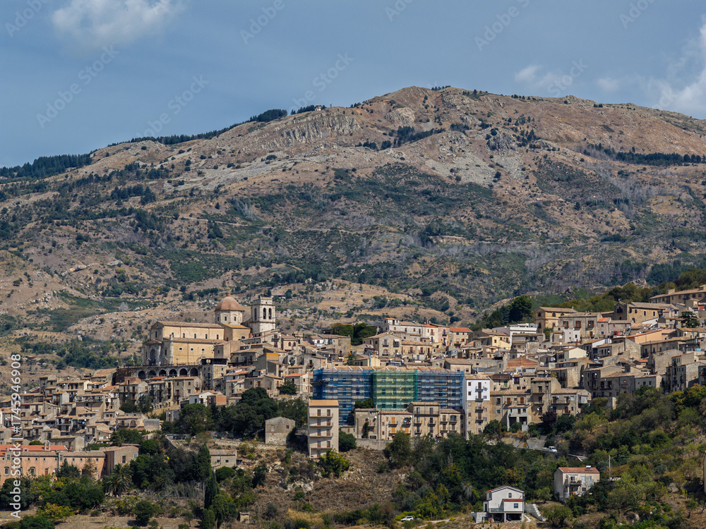 Fototapeta premium Aerial drone view of Petralia Sottana, a historic Sicilian mountain town surrounded by scenic hills and the Madonie Mountains, featuring traditional stone houses and panoramic landscapes, Sicily Italy