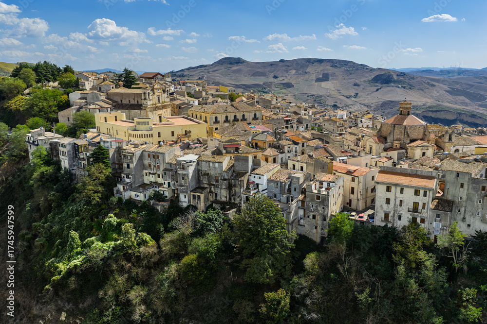 Naklejka premium Aerial drone view of Polizzi Generosa, a picturesque Sicilian mountain town perched on rocky cliffs showcasing traditional stone buildings and panoramic views of the Madonie Mountains, Sicily, Italy