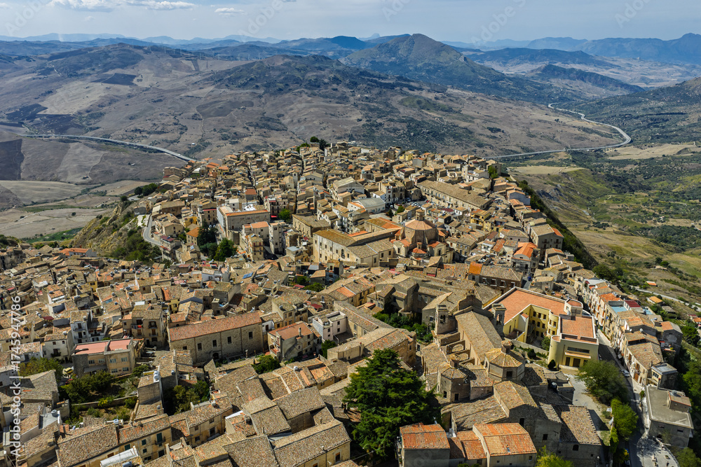 Fototapeta premium Aerial drone view of Polizzi Generosa, a picturesque Sicilian mountain town perched on rocky cliffs showcasing traditional stone buildings and panoramic views of the Madonie Mountains, Sicily, Italy