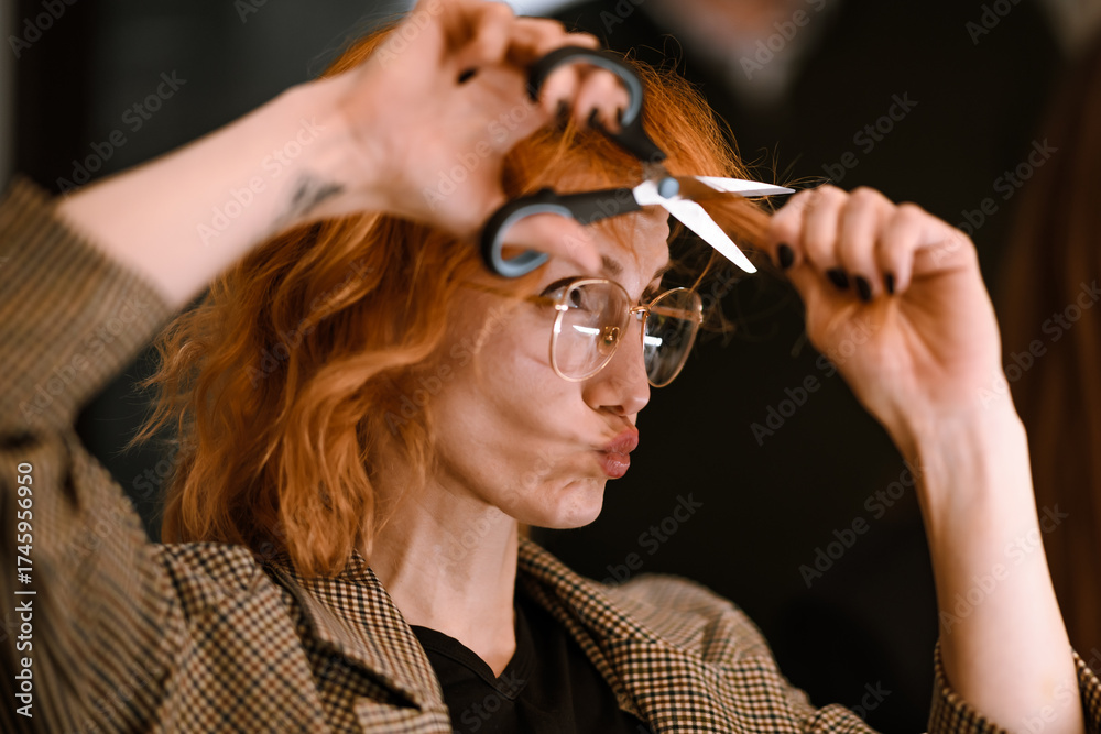Fototapeta premium Woman playfully posing with scissors while showing off her stylish haircut in a creative space during daytime