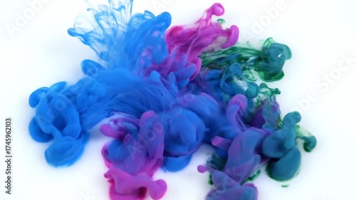 Vibrant Blue, Purple, and Green Ink Swirling in Water on White Background.