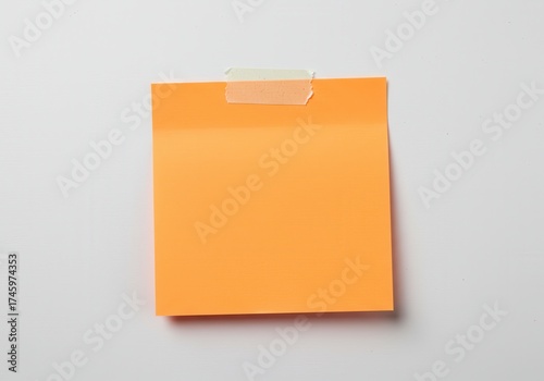 Orange sticky note attached with tape on a white surface.
